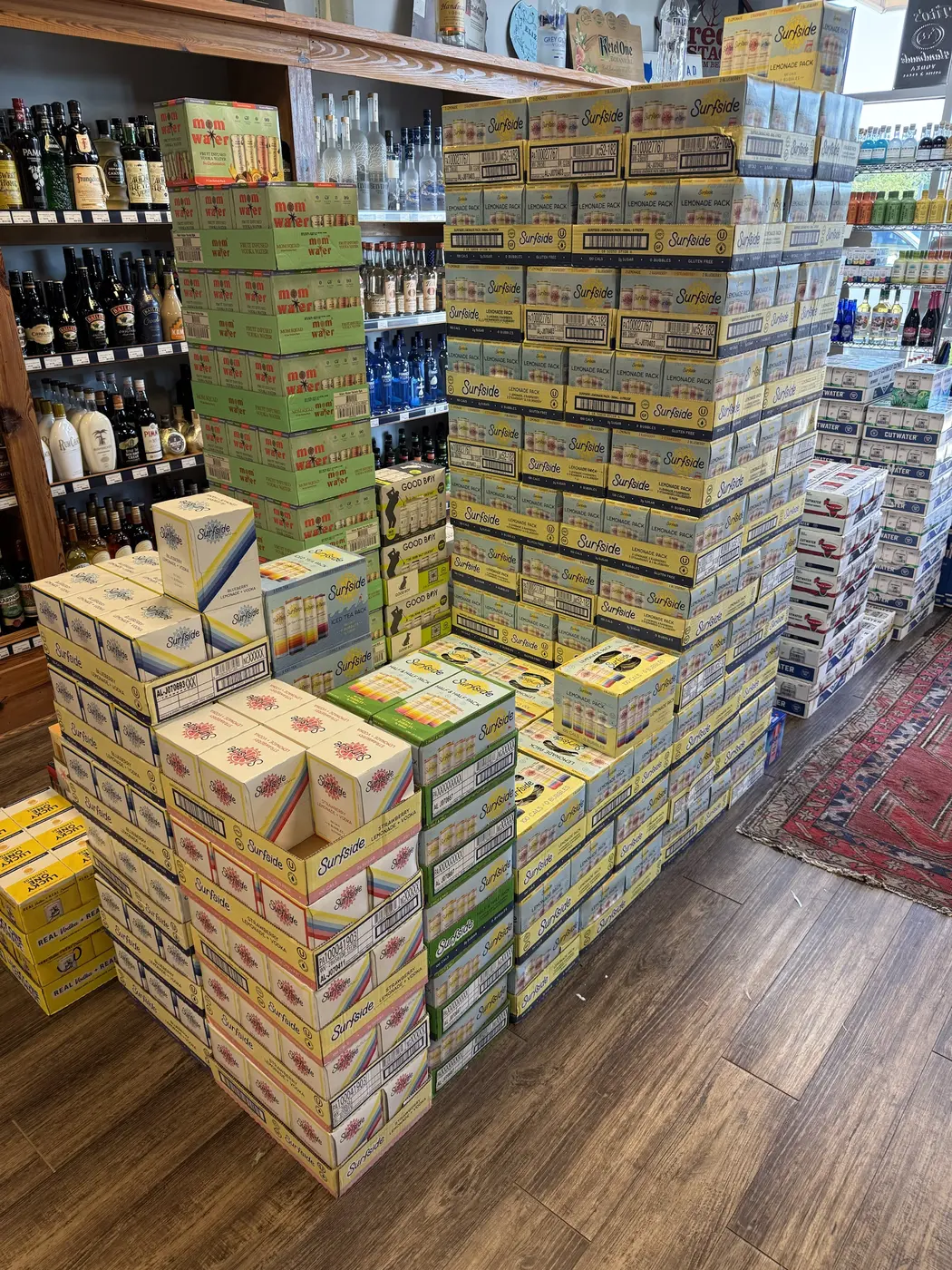 Surfside lemonade, Mom Water and Cutwater cases stacked by the wine shelves